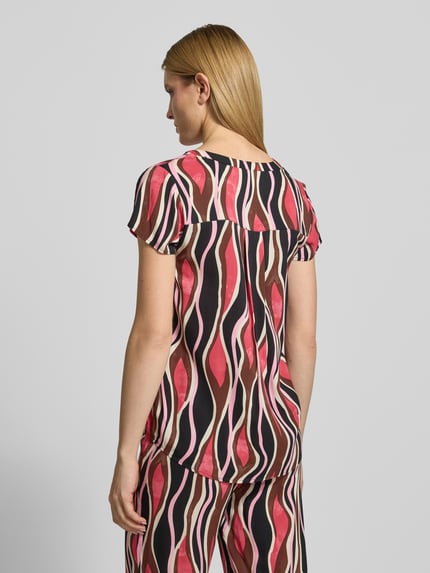 Frauenmodel trägt Damen T-Shirt aus reiner Viskose im Regular-Fit Modell 'Cammi' von Soyaconcept mit Tunika-Ausschnitt, Rückenlänge bei Größe S 69 cm, Ärmellänge 15 cm, farbig gemustert, abstrakte Formen, glatte Textur, Ganzkörperansicht Rückansicht.
