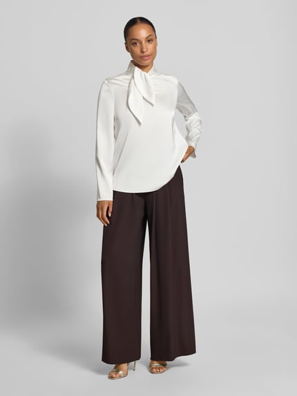 Vrouwenmodel draagt Wide Leg Stoffhose met Reißverschlusstaschen van Rinascimento, Materiaalmix met stretch, wide leg, elastische band, zij-ritszakken, bandwijdte maat S 37 cm, binnenbeenlengte maat S 82 cm, donkere broek, rechte lijnen, zachte stof, Ganzkörperansicht van voren.
