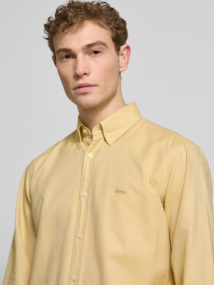 Männermodel trägt Regular Fit Freizeithemd aus reiner Baumwolle Modell 'Rickert' von BOSS Orange in Gelb, Nahaufnahme Oberkörper.