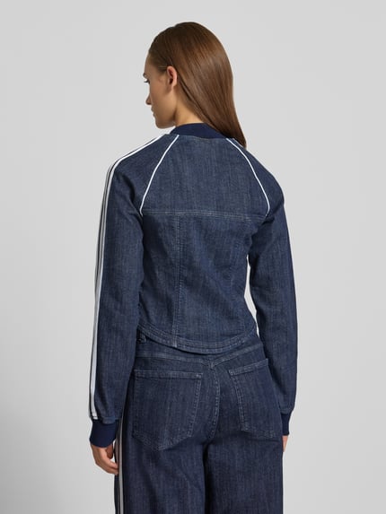Männermodel trägt Regular Fit Jeansjacke aus Baumwoll-Mix Modell 'SUPERSTAR' von adidas Originals, dunkles Blau mit weißen Streifen, strukturierte Textur, Ganzkörperansicht Rückansicht.