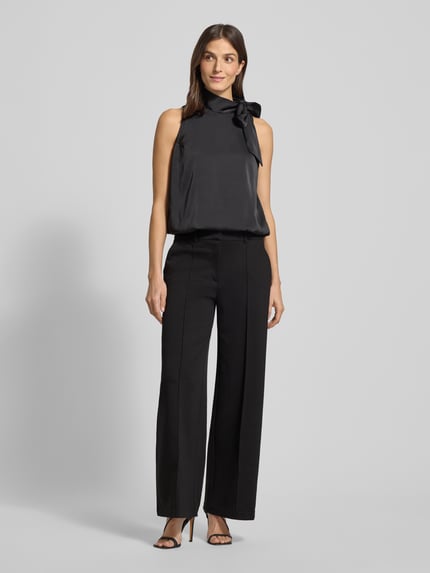 Frauenmodel trägt Wide Leg Stoffhose mit fixierten Bügelfalten Modell 'KATE' von ICHI, Material-Mix mit Viskose-Anteil, Paspeltaschen am Gesäß, Ganzkörperansicht von vorne.
