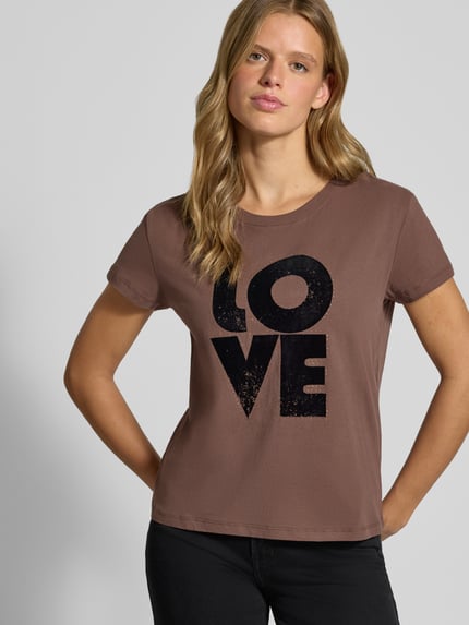 Frauenmodel trägt Regular Fit T-Shirt aus reiner Baumwolle Modell 'BEATRISA' von Pepe Jeans in Braun mit schwarzem Schriftzug, Nahaufnahme Oberkörper, Damen T-Shirt von Pepe Jeans.