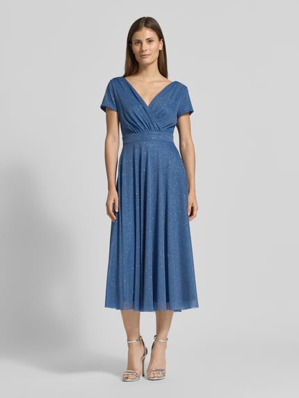 Vrouwenmodel draagt Schimmerndes Cocktailkleid mit V-Ausschnitt van Vera Mont, glanzend blauwe tule, a-lijn midi-jurk, ruglengte maat 36: 100 cm, borstwijdte maat 36: 42 cm, geheel vooraanzicht.