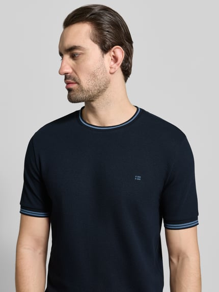 Męski model nosi T-shirt mit Strukturmuster und Rundhalsausschnitt von Christian Berg Men, mieszanka bawełny i elastanu, krój regular fit, okrągły dekolt, głęboka granatowa kolorystyka, fakturowany wzór, długość tyłu w rozmiarze M: 70 cm. Zbliżenie na górną część ciała z przodu.