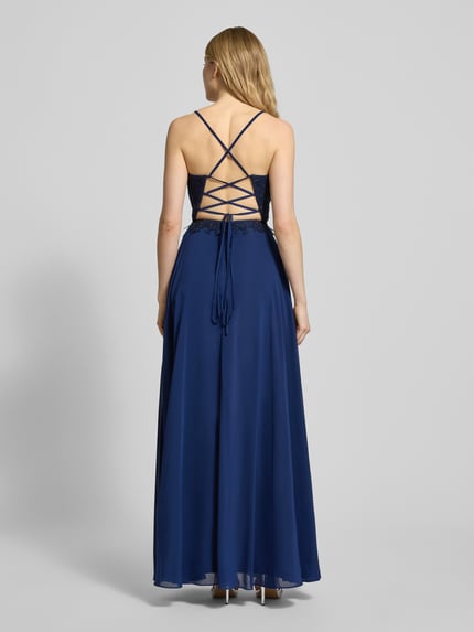 Modelka nosi dopasowaną suknię wieczorową z ozdobami marki LUXUAR FASHION w kolorze granatowym, maxi, koronkowy detal, widok z tyłu.