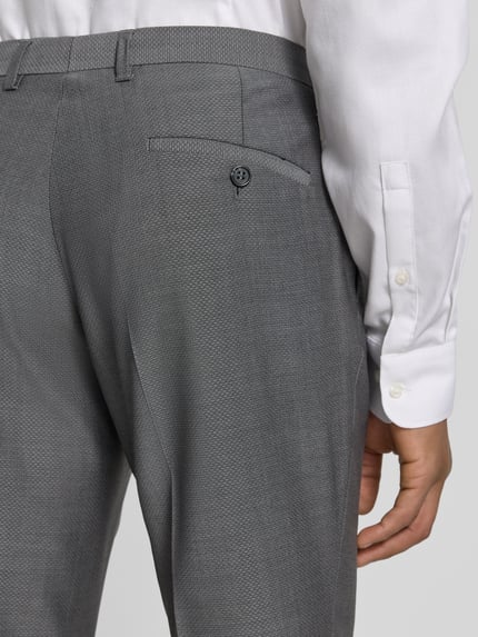 Męski model nosi Slim Fit Anzughose mit Bügelfalten Modell 'Cedric' von CG - Club of Gents, szara bawełna, detal z tyłu, Szerokość w rozmiarze 50: 44 cm, długość nogawki od wewnątrz 103 cm, krój slim fit