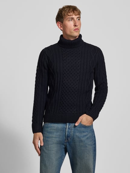 Männermodel trägt dunkelblauen Rollkragenpullover mit Zopfmuster von Superdry, Slim Fit, Material-Mix mit Leinen, Nahaufnahme Oberkörper.