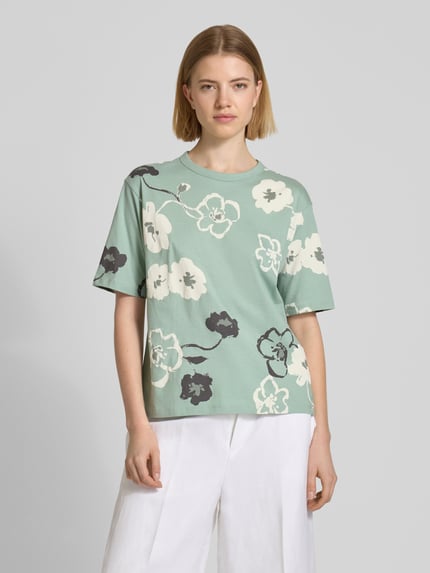 Modelka kobieca nosi T-Shirt im Allover-Look mit Rundhalsausschnitt od JAKE*S STUDIO WOMAN, czysta bawełna, krój regular fit, zielone z jasnym kwiatowym wzorem, długość tyłu w rozmiarze S: 57 cm, widok całej sylwetki z przodu