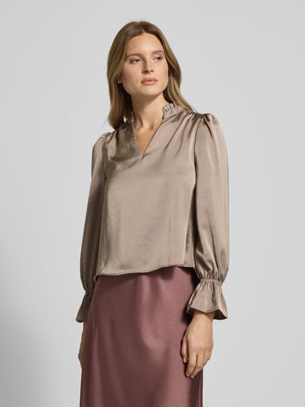 Frauenmodel trägt Relaxed Fit Bluse mit Tunika-Kragen Modell 'Amara' von Neo Noir im Elastischer-Material-Mix mit Rüschenbesatz, Ganzkörperansicht von vorne.