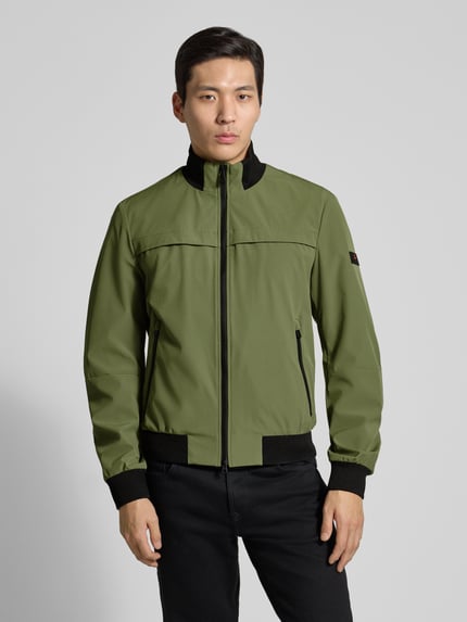 Männermodel trägt grüne Jacke mit Stehkragen Modell 'POTOSI' von Peuterey aus Stretch-Materialmix, schwarze Details, Ganzkörperansicht von vorne.