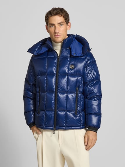 Männermodel trägt Steppjacke mit Zweiwege-Reißverschluss von Armani Exchange in glänzendem Blau, sichtbare Reißverschlusstaschen, Ganzkörperansicht von vorne, Herren Steppjacke, Slim Fit, Kapuze mit Tunnelzug, Label-Detail.