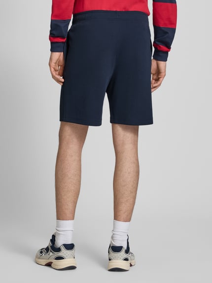 Männermodel trägt Shorts mit elastischem Bund und Label-Stitching von CHAMPION in Dunkelblau, Baumwoll-Mix, Ganzkörperansicht Rückansicht