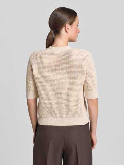 Frauenmodel trägt Cardigan mit V-Ausschnitt Modell 'Temmy' von Someday, Material-Mix mit Baumwoll-Anteil, Regular-Fit, Knopfleiste, 1/2-Arm, Rückenlänge bei Größe 36: 50 cm, Ärmellänge bei Größe 36: 30 cm, cremefarben, grob gestrickte Textur, Ganzkörperansicht Rückansicht