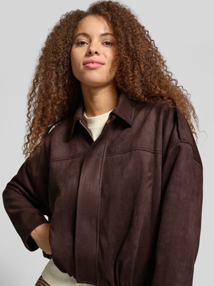 Frauenmodel trägt Kurzmantel mit Schulterklappen von ONLY in Dunkelbraun, leicht strukturierte Oberfläche, Nahaufnahme Oberkörper, Damen Kurzmantel von ONLY.