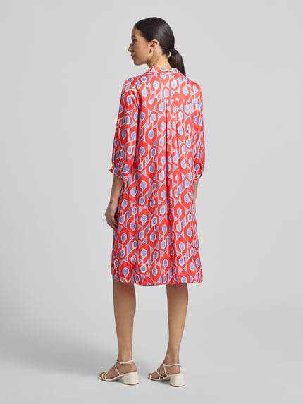 Modelka nosi knielanges Hemdblusenkleid mit V-Ausschnitt von Milano Italy, kolorowy wzór, czysta wiskoza, linia A, długość do kolan, kołnierzyk koszulowy, dekolt w serek, długość tyłu w rozmiarze 36: 98 cm, szerokość w rozmiarze 36: 54 cm, długość rękawa w rozmiarze 36: 43 cm, całopostaciowy widok z tyłu.