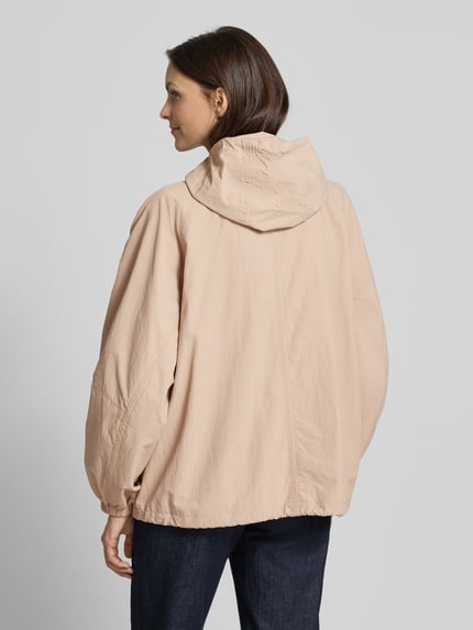 Frauenmodel trägt Jacke mit Kapuze und Pattentaschen von Jake*s Casual in Beige mit Relaxed-Fit, Rückenansicht Ganzkörperansicht. Rückenlänge 66 cm, Schulterbreite 41 cm, Brustweite 56 cm, Ärmellänge 65 cm bei Größe 36, Kapuze mit Tunnelzug, Reißverschluss, Pattentaschen.