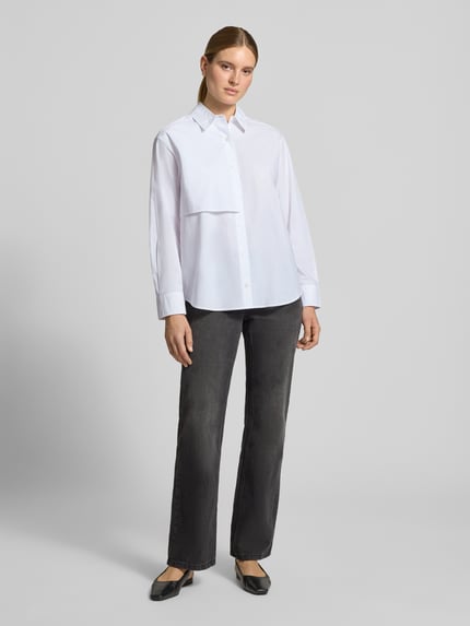 Frauenmodel trägt Relaxed Fit Hemdbluse aus reiner Baumwolle Modell 'Lovani' von Samsøe Samsøe, weiß, mit Knopfleiste, Ganzkörperansicht von vorne. Rücklänge 73 cm, Ärmellänge 60 cm.