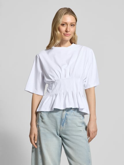 Modelka nosi damski t-shirt z mieszanki bawełny i elastanu, taliowany krój, model 'inez' od Gestuz, okrągły dekolt, długość tyłu w rozmiarze S: 54 cm, widok całej sylwetki z przodu.
