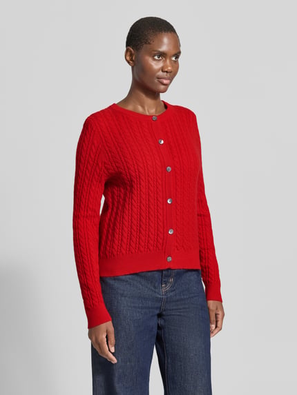 Frauenmodel trägt Regular Fit Strickjacke aus reinem Kaschmir mit Zopfmuster von Christian Berg Woman in Rot mit Knopfleiste, Nahaufnahme Oberkörper.