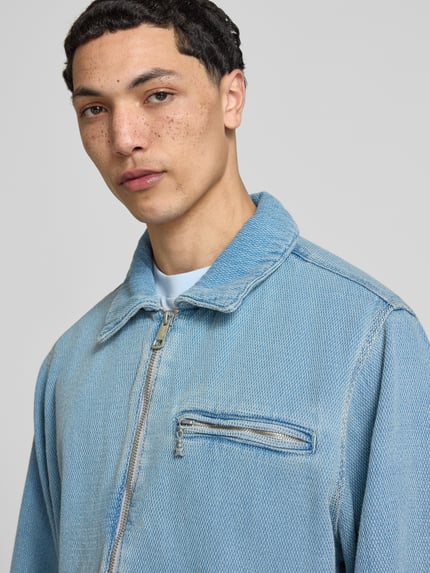 Männermodel trägt Regular Fit Jeansjacke aus reiner Baumwolle Modell 'ELZO' von HUGO Blue in hellem Denim, Nahaufnahme Oberkörper.