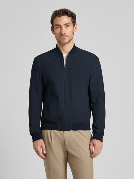 Männermodel trägt donkerblauwe bomberjack met steekzakken, materiaalmix met stretch, recht model, model 'Indro' van JOOP! collectie, geheelvooraanzicht.