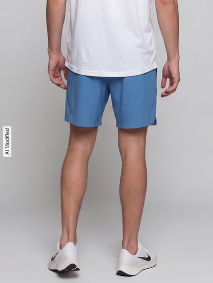 Männermodel trägt Regular Fit Sportshorts mit Logo-Print von Under Armour in Blau, glatte Textur, Ganzkörperansicht Rückansicht, KI-modifiziertes Bild.