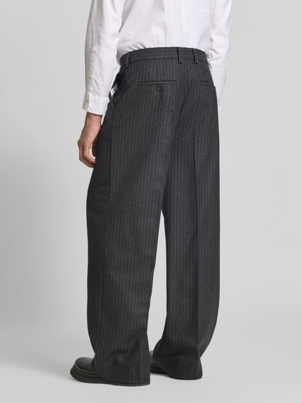 Männermodel trägt Relaxed Fit Stoffhose aus Baumwoll-Mix von Filippa K, grau mit feinen weißen Nadelstreifen, Ganzkörperansicht Rückansicht. Produktdetails: Bundfalten, Knopf- und Reißverschluss, Eingriff- und Gesäßtaschen, Innenbeinlänge 80 cm, Bundweite 45 cm bei Größe 50.