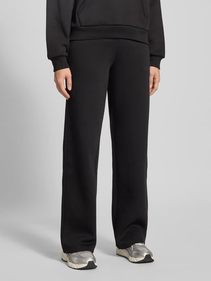 Vrouwenmodel draagt Sweatpants met elastische tailleband van Review, zwart, losse pasvorm, katoenmix, Franse steekzakken, detailopname onderlichaam.