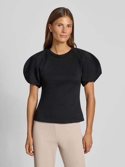 Vrouwenmodel draagt blouse met ballonmouwen van Rinascimento in zwart, Materiaalmix met stretch, getailleerde pasvorm, ronde hals, ruglengte maat S 55 cm, mouwlengte maat S 27 cm. Ganzichaanszicht van voren.