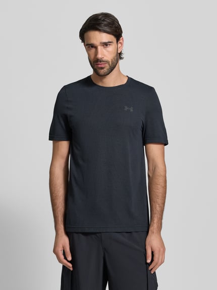 Männermodel trägt schwarzes Slim Fit T-Shirt mit Logo-Print Modell 'Vanish' von Under Armour, Lochmuster, Rundhalsausschnitt, Ganzkörperansicht von vorne.
