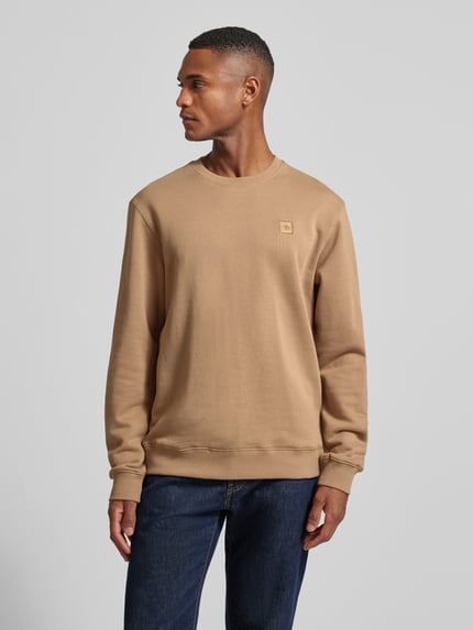 Männermodel trägt Sweatshirt mit Label-Detail von Scotch & Soda in Beige, reine Baumwolle, lockerer Schnitt, gerippte Abschlüsse, Rundhalsausschnitt, Rückenlänge 70 cm, Ärmellänge 68 cm, Ganzkörperansicht von vorne.