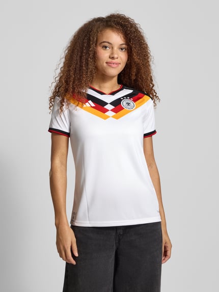 Vrouwenmodel draagt Trikot met V-hals Model 'DFB' van adidas Sportswear, slanke pasvorm, wit met gekleurde details, voorkant totaalbeeld.