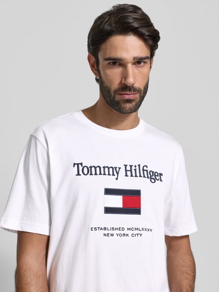 Männermodel trägt Regular Fit T-Shirt aus reiner Baumwolle von Tommy Hilfiger, weiß, unifarben, kurzer Ärmel, Nahaufnahme Oberkörper.