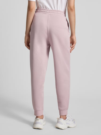 Frauenmodel trägt Sweatpants mit Label-Stitching und elastischem Bund von PUMA in Rosa, Baumwoll-Mix, Relaxed Fit, Ganzkörperansicht Rückansicht.