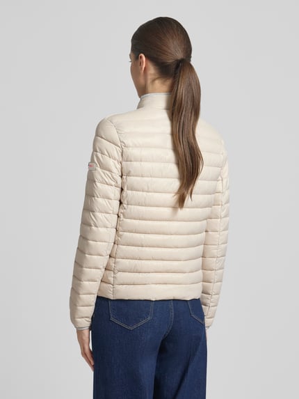 Vrouwenmodel draagt Steppjacke mit Reißverschlusstaschen Modell 'SISTER JUDY' van Frieda & Freddies, slim fit, opstaande kraag, rits, ritszakken, ruglengte maat 36: 56 cm, schouderbreedte maat 36: 41 cm, borstwijdte maat 36: 47 cm, mouwlengte maat 36: 61 cm, beige, horizontale stiksels, gestructureerd oppervlak, Ganzkörperansicht Rückansicht.