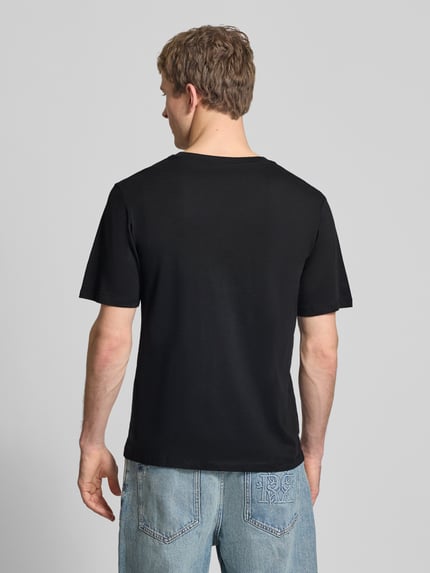 Męski model nosi T-Shirt mit Rundhalsausschnitt Modell 'HONOLULU' od Jack & Jones, czarny, bawełna, krój regular fit, długość tyłu 68 cm, widok całej sylwetki z tyłu.