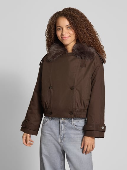 Vrouwenmodel draagt Regular Fit Jacke mit Kunstpelz van Gina Tricot in bruin katoenmix, reverskraag, schoudertrensjes, elastische band, knoopsluiting, vooraanzicht hele lichaam. Ruglengte maat S: 50 cm, schouderbreedte: 50 cm, borstwijdte: 58 cm, mouwlengte: 53 cm.