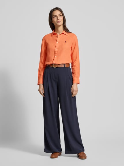 Modelka kobieca nosi Hemdbluse mit Knopfleiste od Polo Ralph Lauren z lnu, luźny krój, pomarańczowy kolor, widok całej sylwetki z przodu.
