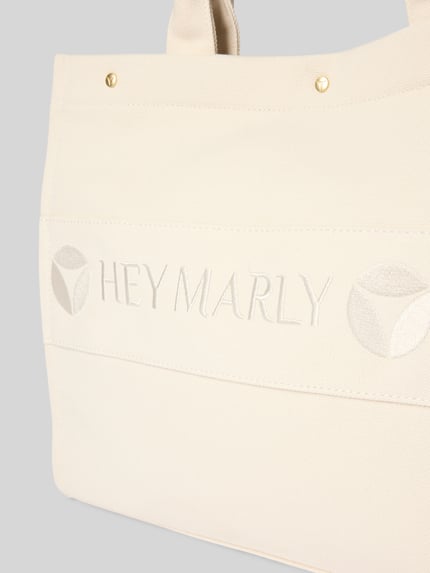 Produktfoto, cremefarbene Handtasche mit Logo-Stitching Modell 'Signature' von Hey Marly, Strukturstoff, goldene Details, Kontext: Damen Handtasche mit Hauptfach, Druckknopfverschluss, Schulterriemen, Reißverschlussfach, Breite 42 cm, Länge 31 cm, Tiefe 15 cm, Länge Schulterriemen 55 cm.