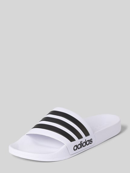 Produktfoto, Badeschuhe mit Label-Prägung Modell 'ADILETTE SHOWER' von adidas Sportswear, białe z czarnymi paskami, unikalna faktura podeszwy, otwarty przód, płaski obcas, wsuwane, minimalistyczny styl