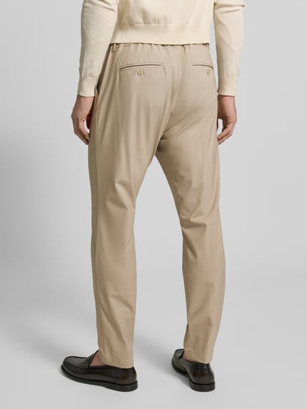 Männermodel trägt Hose aus Schurwolle-Mix mit französischen Eingrifftaschen von CRUNA in Beige, elastischer Bund, Ganzkörperansicht Rückansicht.