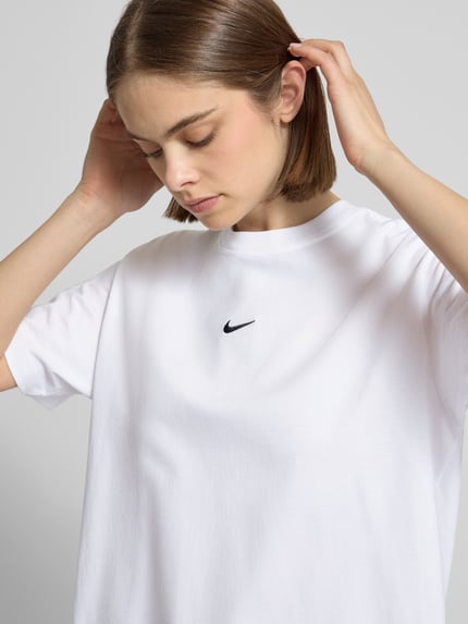 Frauenmodel trägt T-Shirt mit Logo und Rundhalsausschnitt von Nike aus reiner Baumwolle im Relaxed Fit, Nahaufnahme Oberkörper.