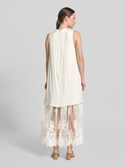 Frauenmodel trägt Relaxed-Fit Maxikleid aus Viskose-Mix Modell 'Tenley' von Copenhagen Muse mit Spitzenbesatz und Ärmelloses-Design, Leinen-Viskose-Anteil in Creme, semitransparent mit Spitze, Ganzkörperansicht Rückansicht.