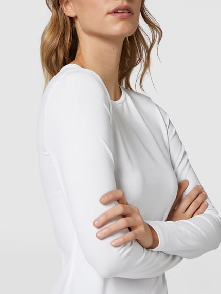 Vrouwenmodel draagt wit shirt met lange mouwen van mix van katoen en elastaan, slim fit, model 'Smilla' van Opus, nahaufnahme bovenlichaam. Ruglengte maat 36: 63 cm.