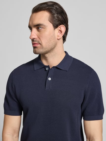 Mannelijk model draagt Slim Fit Poloshirt met structuurpatroon model 'Johan' van Christian Berg Men van puur katoen, korte mouw, polokraag, donkerblauw, detailopname bovenlichaam.