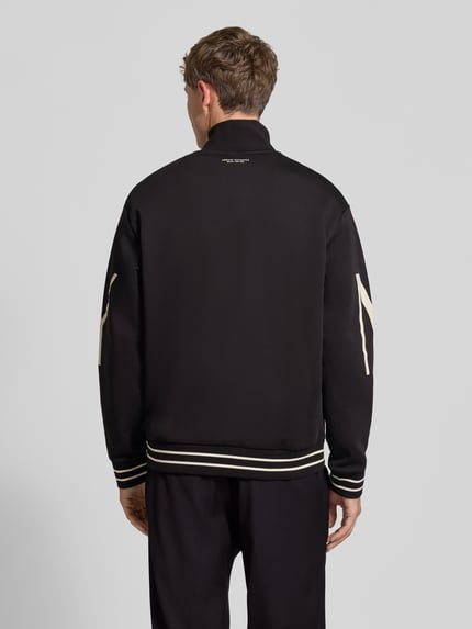 Männermodel trägt Sweatjacke aus Baumwoll-Mix von Armani Exchange in Schwarz mit cremefarbenem Label-Print und gerippten Abschlüssen, Rückenlänge 67 cm, lockere Passform, Ganzkörperansicht Rückansicht