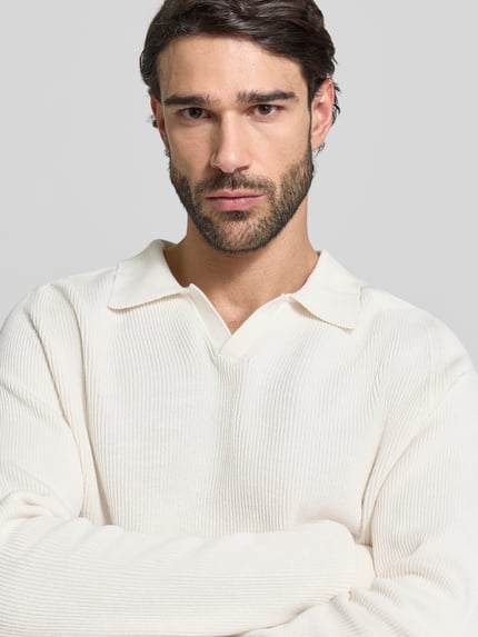 Męski model nosi Strickpullover aus reiner Baumwolle Modell 'NORDIN' od Casual Friday, kremowy, prążkowana faktura, luźny krój, zbliżenie górnej części ciała.