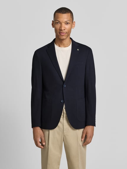 Männermodel trägt Modern Fit Sakko mit Brustleistentasche von Pierre Cardin, Baumwoll-Mix, Reverskragen, Knopfleiste, Label-Detail, seitliche Eingrifftaschen, Rückenlänge 73 cm, Schulterbreite 40 cm, Ärmellänge 63 cm, dunkler Farbton, feine Textur, Ganzkörperansicht von vorne.