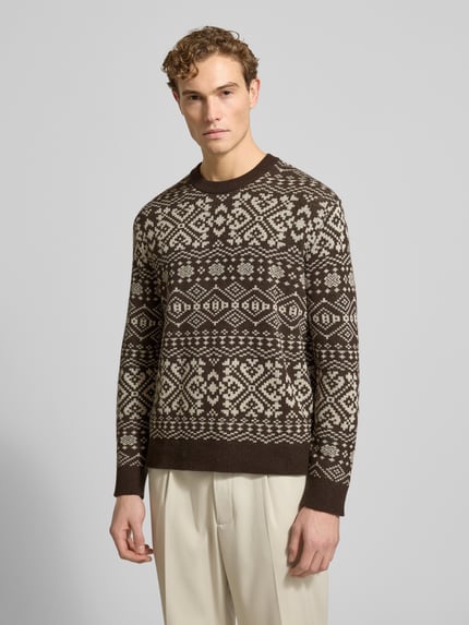 Männermodel trägt Regular Fit Strickpullover aus Woll-Mix Modell 'HOLGER' von SELECTED HOMME in Braun-Beige Jacquard-Optik, Ganzkörperansicht von vorne.