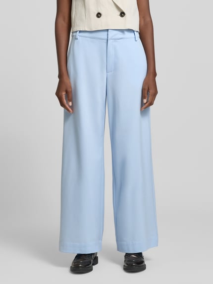 Kobiece modelka nosi spodnie z szerokimi nogawkami Wide Leg Hose mit Viskose-Anteil Modell 'Hace' od My Essential Wardrobe, jasnoniebieski, mieszanka materiałów z dodatkiem wiskozy, wpuszczane kieszenie, zapięcie na haftkę i zamek błyskawiczny, szerokość w rozmiarze 36: 40 cm, długość wewnętrzna nogawki w rozmiarze 36: 79 cm, widok pełnej sylwetki z przodu.